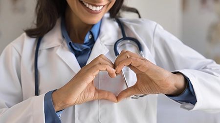 Professionnelle de la santé souriante faisant un symbole de cœur avec ses mains