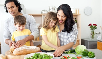 Une mère, un père et deux enfants préparant ensemble un repas sain dans une cuisine.