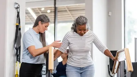 Un professionnel de la santé aide une femme à faire de la physiothérapie dans un escalier.