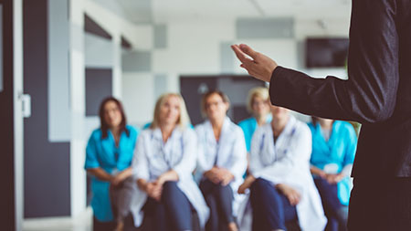 Un groupe de professionnels de santé écoute une personne qui s’adresse au groupe