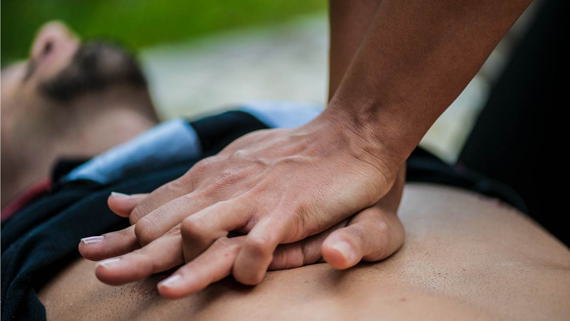 Un homme est allongé à plat pendant que quelqu'un pratique la RCR sur sa poitrine nue.